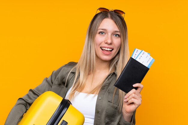 Jonge blondevrouw in vakantie met koffer en paspoort