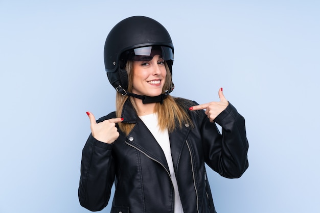 Jonge blondevrouw met een motorhelm over geïsoleerde blauwe muur
