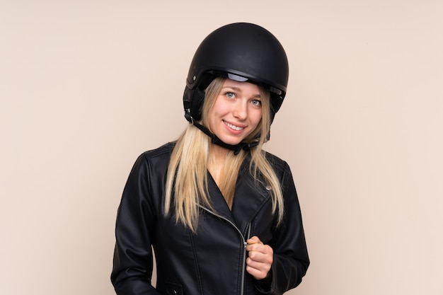 Jonge blondevrouw met een motorhelm over geïsoleerde muur