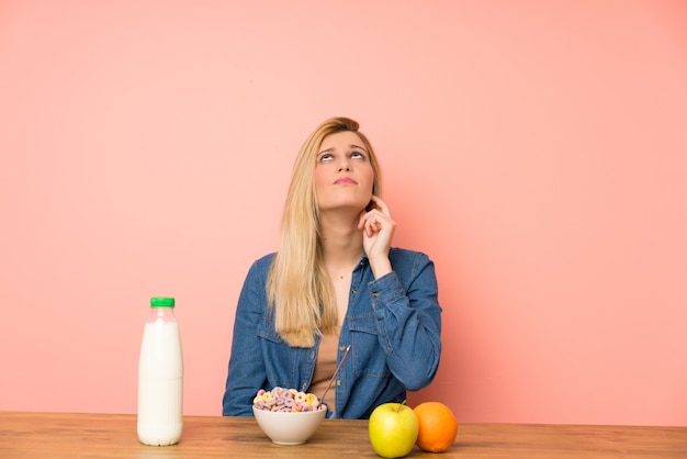 Jonge blondevrouw met kom graangewassen die en een idee bevinden zich denken