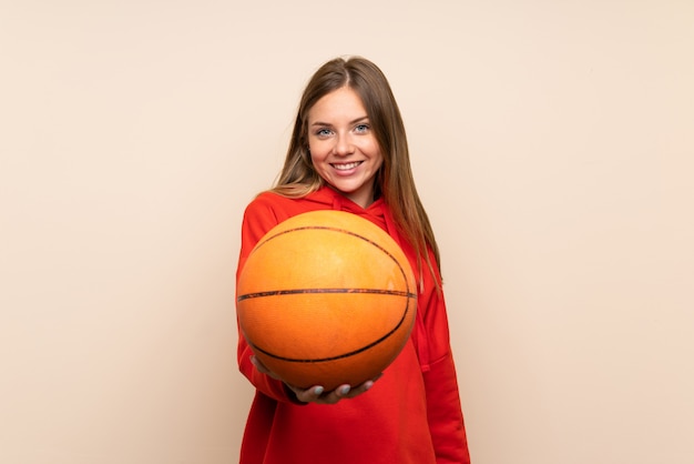 Jonge blondevrouw over geïsoleerde muur met bal van basketbal