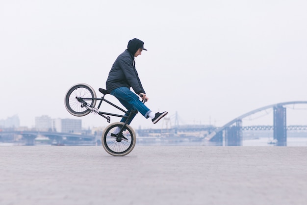 Jonge BMX-fietser rijdt op het voorwiel op het minimalistische stedelijke landschap. BMX-concept.