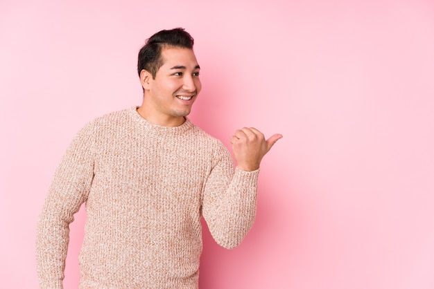 Jonge bochtige man poseren in een roze geïsoleerde punten met duimvinger weg, lachen en zorgeloos.