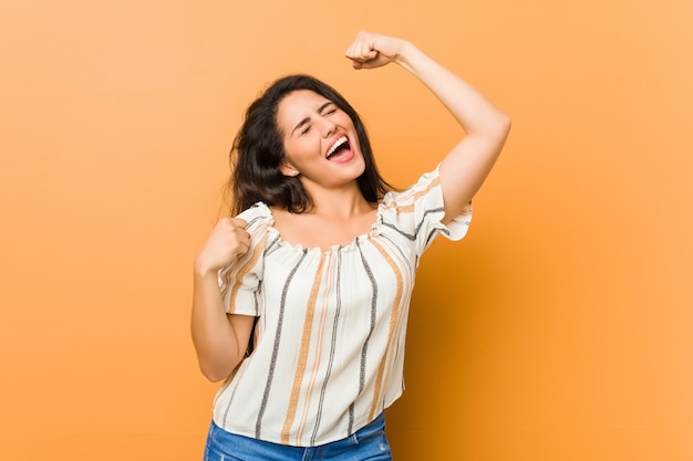 Jonge bochtige vrouw die vuist opheft na een overwinning, winnaarconcept.