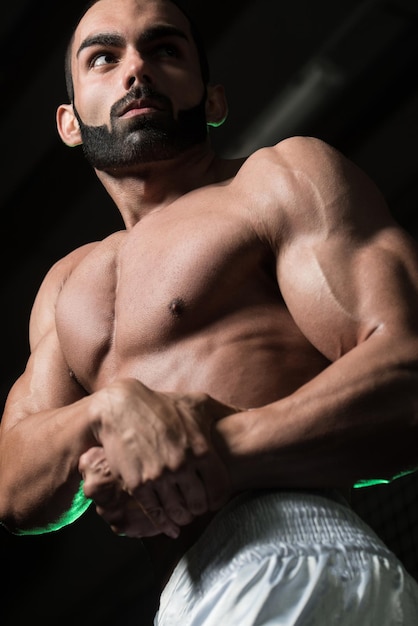 Jonge bodybuilder buigen spieren kant borst pose