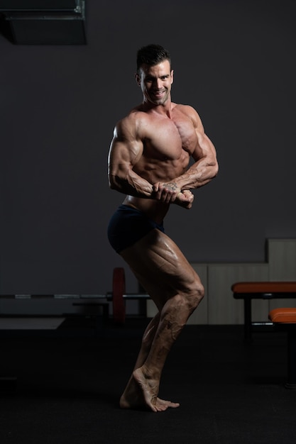 Jonge bodybuilder buigen spieren kant borst pose