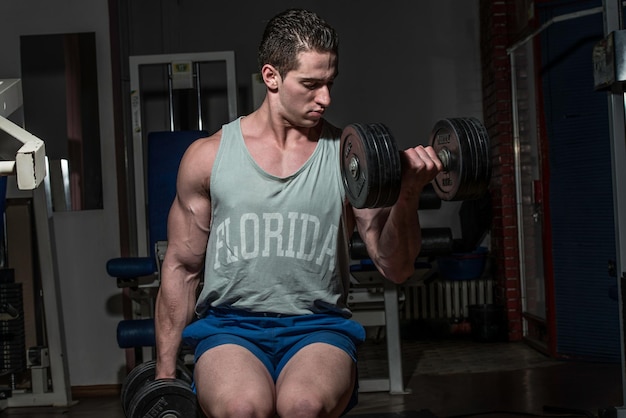 jonge bodybuilder doet zware oefening voor biceps met dumbbell