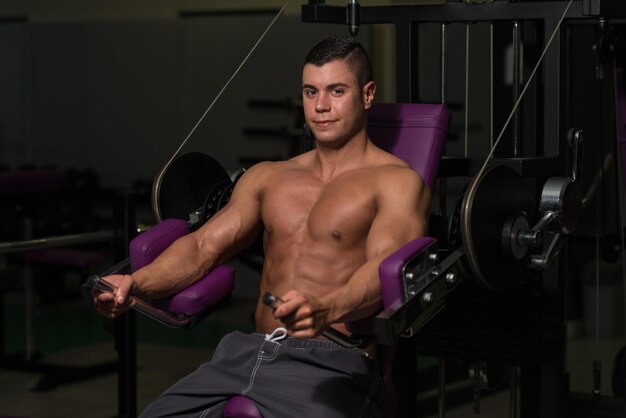 Jonge bodybuilder doet zware oefening voor borst op machine