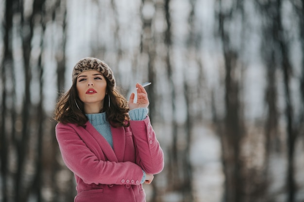 Jonge Bosnische vrouw roken en poseren in het bos in de winter