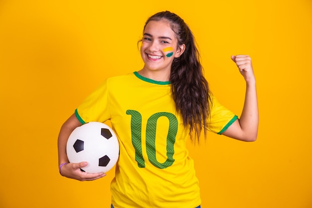 Jonge Braziliaanse cheerleader met een bal in haar hand en beschilderd gezicht