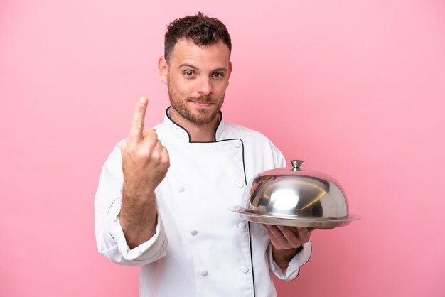 Jonge Braziliaanse chef-kok met dienblad geïsoleerd op roze achtergrond die komend gebaar doet