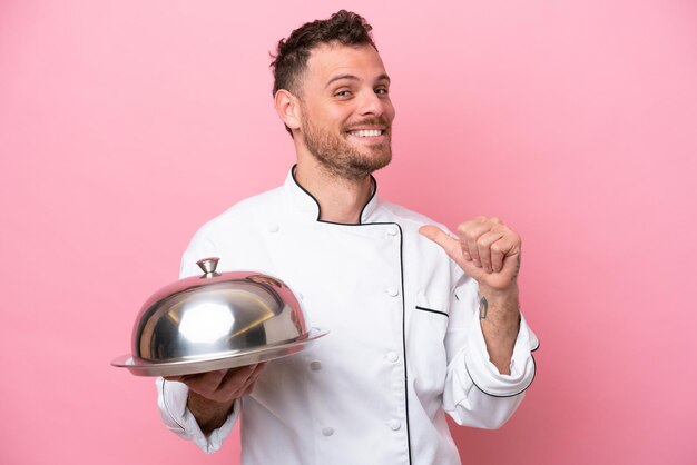 Jonge Braziliaanse chef-kok met dienblad geïsoleerd op roze achtergrond trots en zelfvoldaan