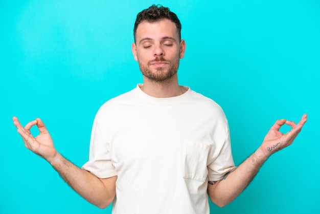 Jonge Braziliaanse man geïsoleerd op blauwe achtergrond in zen pose