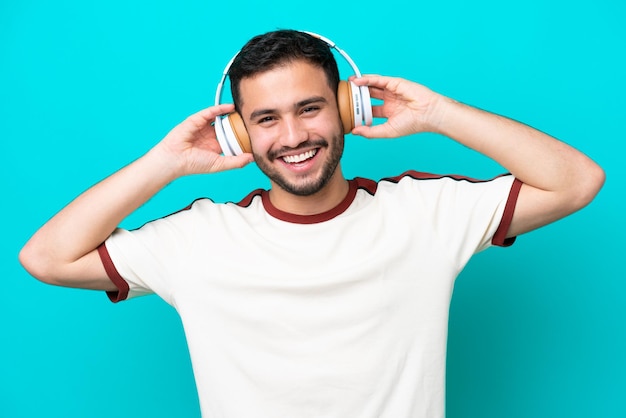 Jonge Braziliaanse man geïsoleerd op blauwe achtergrond muziek luisteren