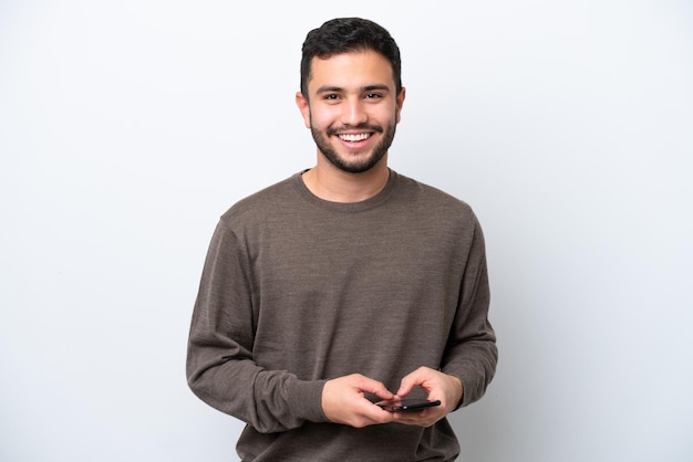 Jonge braziliaanse man geïsoleerd op een witte achtergrond die een bericht verzendt met de mobiel