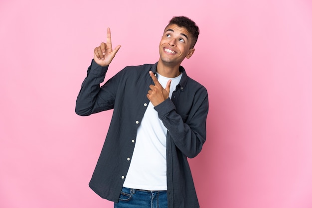 Jonge braziliaanse man geïsoleerd op roze achtergrond wijzend met de wijsvinger een geweldig idee