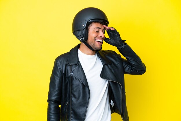 Jonge Braziliaanse man met een motorhelm geïsoleerd op een gele achtergrond lacht veel