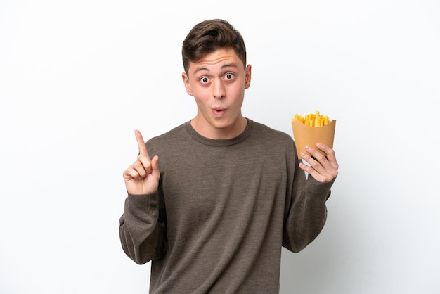 Jonge Braziliaanse man met gefrituurde chips geïsoleerd op een witte achtergrond met de bedoeling de oplossing te realiseren terwijl hij een vinger optilt