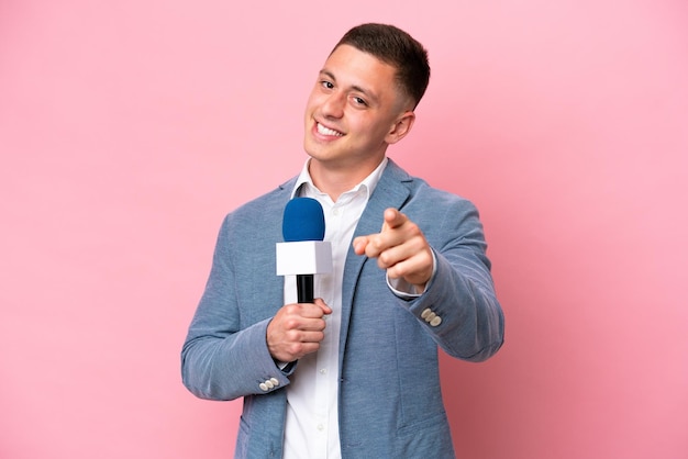 Jonge braziliaanse presentator man geïsoleerd op roze achtergrond wijzend naar voren met gelukkige uitdrukking