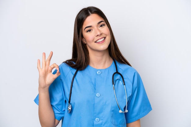 Jonge Braziliaanse verpleegstervrouw die op witte achtergrond wordt geïsoleerd die ok teken met vingers toont