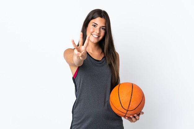 Jonge Braziliaanse vrouw die basketbal speelt geïsoleerd op een witte achtergrond gelukkig en drie tellen met vingers
