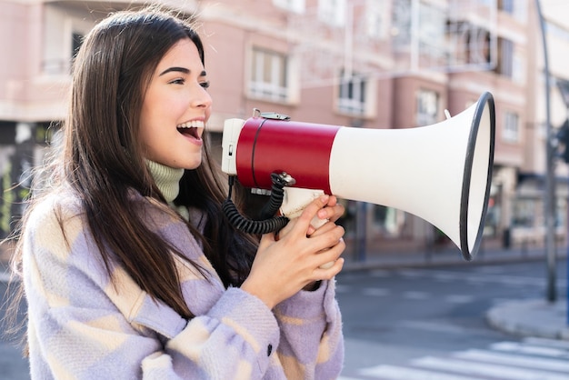 Jonge Braziliaanse vrouw die buiten door een megafoon schreeuwt om iets in zijpositie aan te kondigen