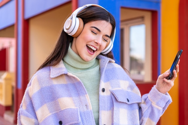 Jonge Braziliaanse vrouw die buiten muziek luistert en gitaargebaar doet