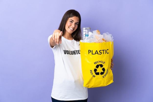 Jonge Braziliaanse vrouw die een zak vol plastic flessen houdt om geïsoleerd te recyclen