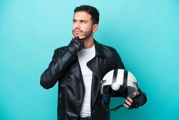 Jonge Braziliaanse vrouw met een motorhelm geïsoleerd op blauwe achtergrond met twijfels