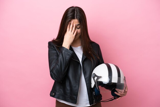 Jonge Braziliaanse vrouw met een motorhelm geïsoleerd op roze achtergrond met vermoeide en zieke expressie