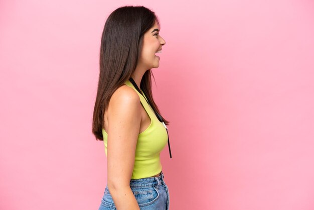 Jonge Braziliaanse vrouw met ID-kaart geïsoleerd op roze achtergrond lachend in laterale positie