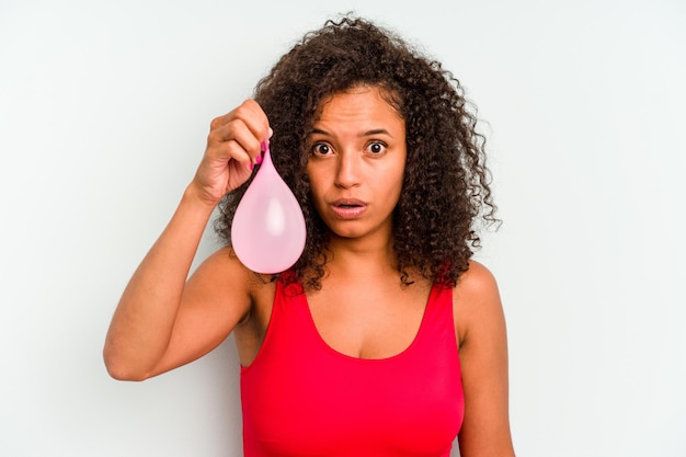 Jonge Braziliaanse vrouw met waterballonnen geïsoleerd op blauwe achtergrond