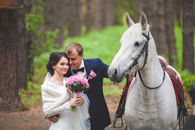 Jonge bruidegom en bruid met paard in park