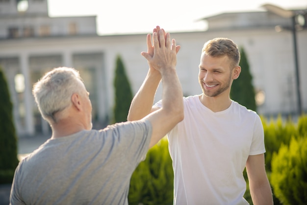 Jonge bruinharige man en grijsharige man die high five geeft