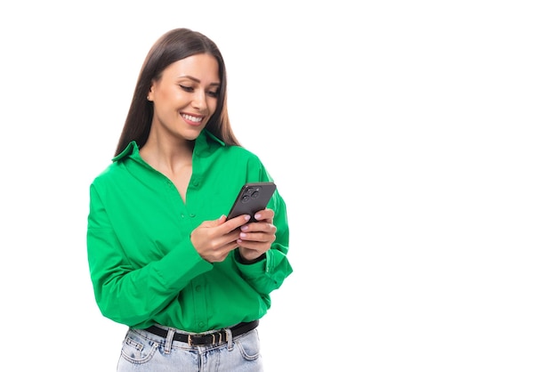 Jonge bruinogige bruinharige vrouw in een groene blouse chatten aan de telefoon