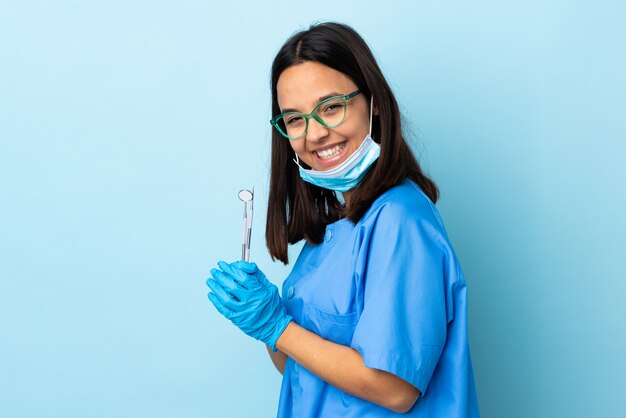 Jonge brunette gemengd ras tandarts vrouw met tools over geïsoleerde applaudisseren