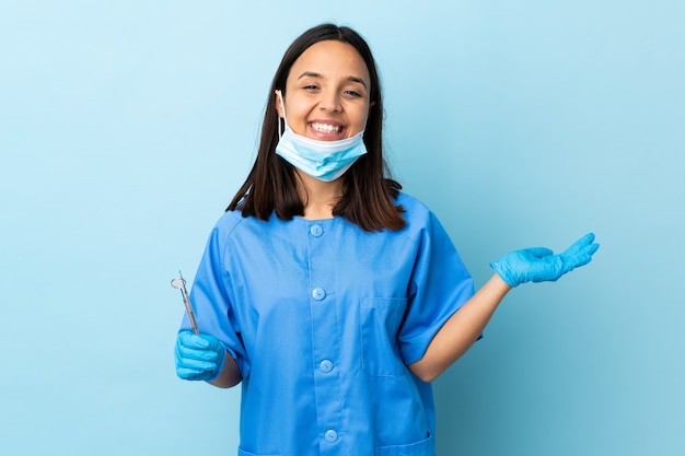 Jonge brunette gemengd ras tandarts vrouw met tools over muur met lege ruimte