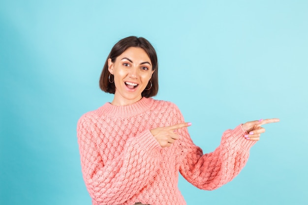 Jonge brunette in roze trui geïsoleerd op blauwe muur