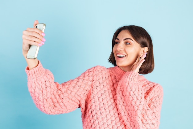 Jonge brunette in roze trui geïsoleerd op blauwe muur