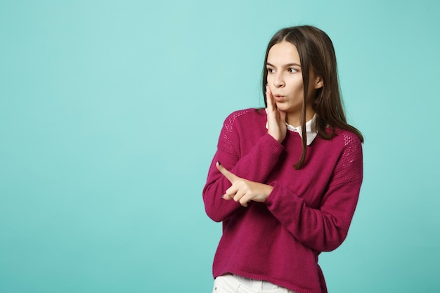 Jonge brunette lachende vrouw meisje in casual kleding poseren geïsoleerd op blauw groene muur achtergrond studio portret. Mensen oprechte emoties levensstijl concept. Bespotten wijzende vinger hand op kopie ruimte