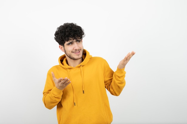 jonge brunette man in gele hoodie staan en poseren.