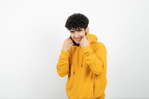 jonge brunette man in gele hoodie staan en poseren.