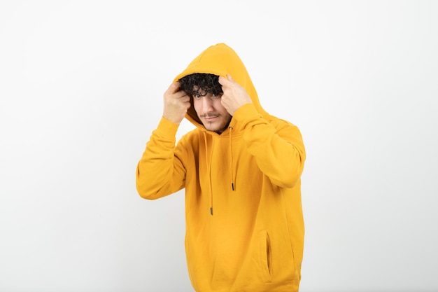 jonge brunette man in gele hoodie staan en poseren.