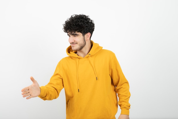 jonge brunette man in gele hoodie staan en poseren.