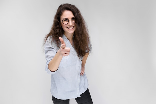 Jonge brunette meid met een bril. Het meisje wijst een vinger naar voren.