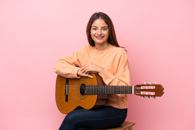 Jonge brunette meid met gitaar over geïsoleerde roze veel glimlachen