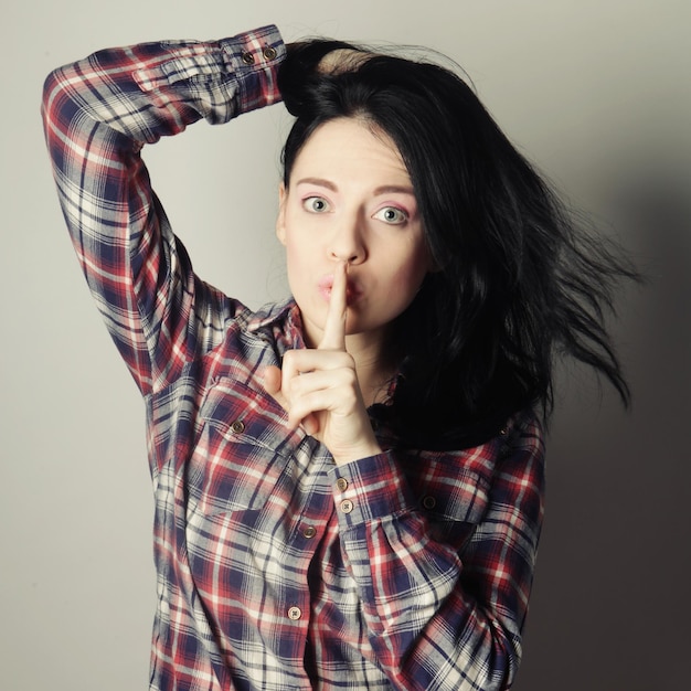 Jonge brunette met een vinger op haar lippen