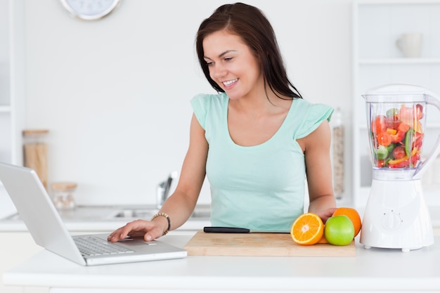 Foto jonge brunette met laptop en vruchten