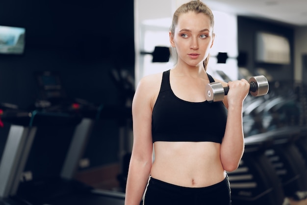 Jonge brunette sportieve vrouw trainen met halter in een sportschool close-up