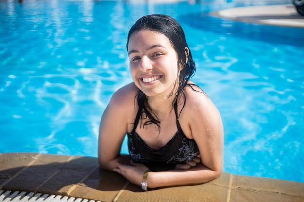 Jonge brunette tienermeisje poseren in een blauw zwembad in een hotel in turkije